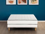 un matelas blanc posé sur un parquet, près d'un mur bleu