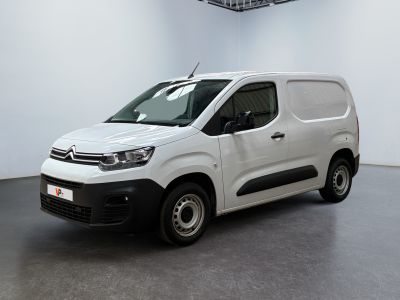 La camionnette blanche est garée dans une grande pièce blanche.