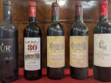 six bottles of wine are lined up on a red table cloth
