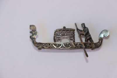 une broche en argent représentant un bateau avec un homme à bord