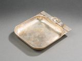 une vieille assiette en argent avec un manche en métal sur un fond gris