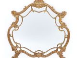 un miroir doré avec un cadre décoratif sur fond blanc