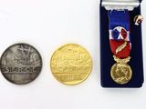 two medals and a coin sitting on a white surface