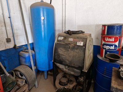 a blue water tank sitting next to a stack of blue barrels