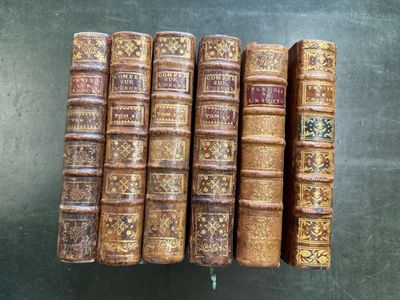 six vieux livres alignés en rang sur une table