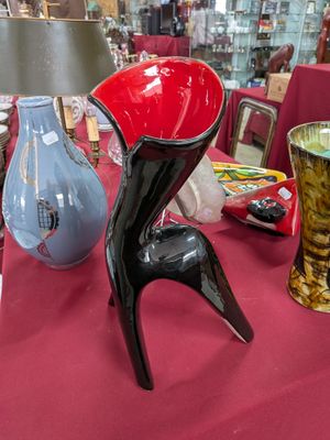 une table recouverte d'une nappe rouge et sur laquelle sont posés des vases