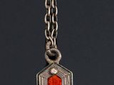 silver and red enamel pendant on a chain on a black background