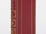 an old book with a red cover and gold trim on a white background