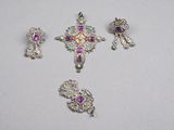 three pieces of silver and purple jewelry on a white surface
