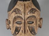 une image représentant un masque en bois au visage noir sur fond blanc