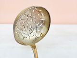 an antique spoon sitting on top of a white table next to a pink wall