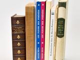 several books are stacked on top of each other on a white surface