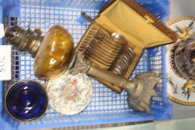 a blue basket filled with silver and glass items
