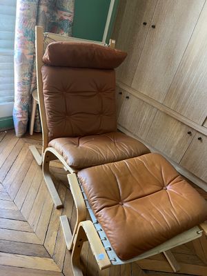 fauteuil inclinable en cuir marron avec repose-pieds, posé sur un sol en bois
