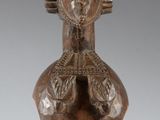 an image of a wooden statue of a woman with her hands on her chest
