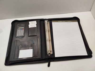 un classeur noir sur lequel sont posés une calculatrice et un bloc-notes