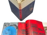 un livre ouvert posé sur une surface blanche, à côté d'un disque bleu