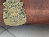 someone is holding a brown purse that has a gold plaque on it
