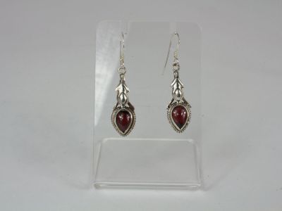 a pair of silver earrings with red stones on them