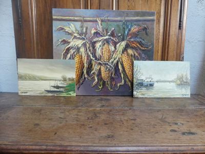 trois tableaux représentant du maïs, posés côte à côte sur une table