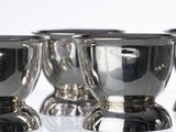 four silver cups sitting on top of a white surface