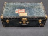 an old suitcase with a label on it sitting on a table