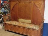 un banc en bois avec un coussin posé dessus, devant un mur recouvert de graffitis