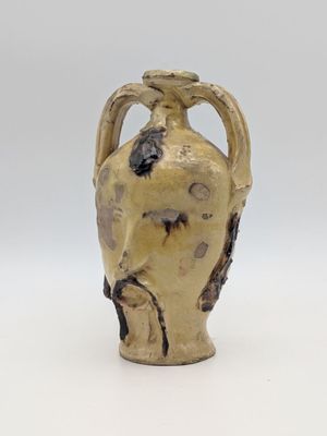 a small vase with a handle on a white surface