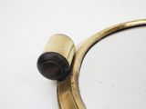 a gold colored mirror with a black knob on it