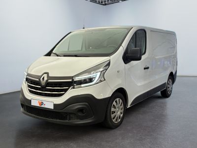 La camionnette blanche est garée dans une grande pièce au sol noir.
