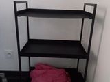 une étagère noire sur laquelle est posée une serviette rose