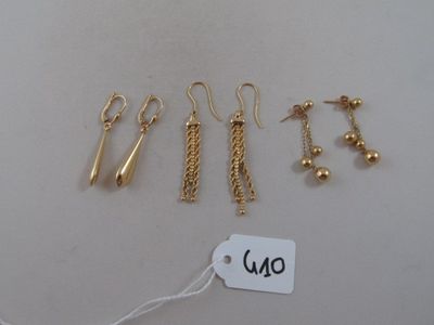 trois paires de boucles d'oreilles en or et une étiquette avec le prix