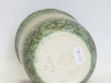 a green and white vase sitting on a white surface