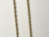 a close up of a gold chain necklace on a white surface
