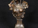 buste en bronze d'une femme sur un socle, sur fond noir