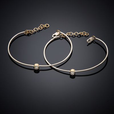 a pair of gold and silver bracelets on a black background