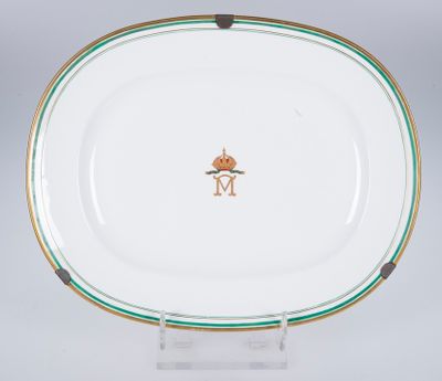 une assiette blanche bordée de vert et ornée d'une couronne dorée