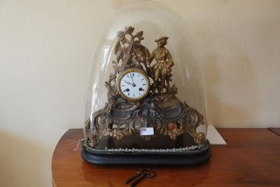 une horloge placée sous un dôme de verre sur une table