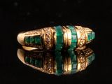 un gros plan d'une bague en or sertie de pierres vertes et de diamants