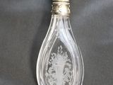 a glass perfume bottle with a silver lid and a gold handle