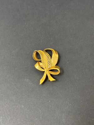 an image of a gold brooch with a leaf on it