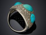 a close up of a ring with turquoise stones on a black surface