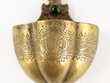 a gold spoon with a green bead in it