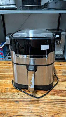 an image of a stainless steel air fryer sitting on a wooden counter