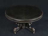 La table est en bois et son plateau est en cuir noir.