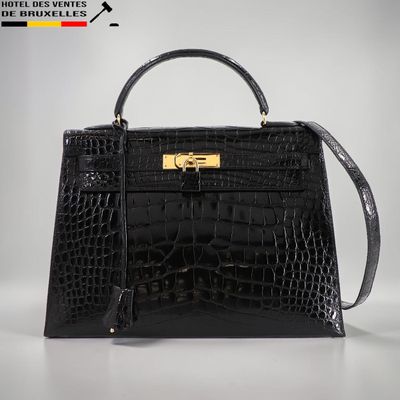 un sac à main en cuir de crocodile noir avec des finitions dorées sur la poignée