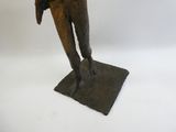 statue en bronze représentant un homme tenant un oiseau, posée sur un socle carré