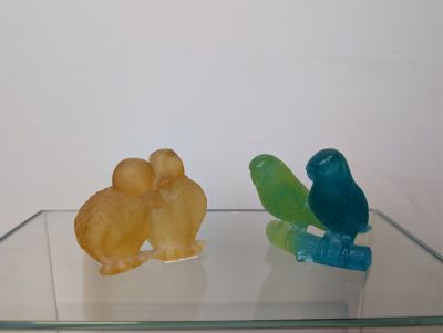 deux figurines d'oiseaux posées sur une étagère en verre