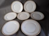 six white plates with gold rims are arranged on a table
