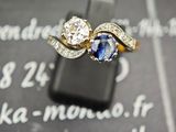 un gros plan d'une bague sertie de diamants et de saphirs, photographiée avec un téléphone portable